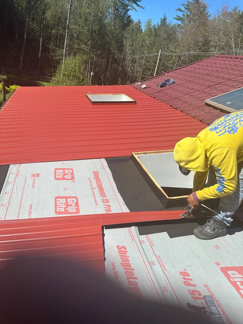 Red metal roof installation around skylights